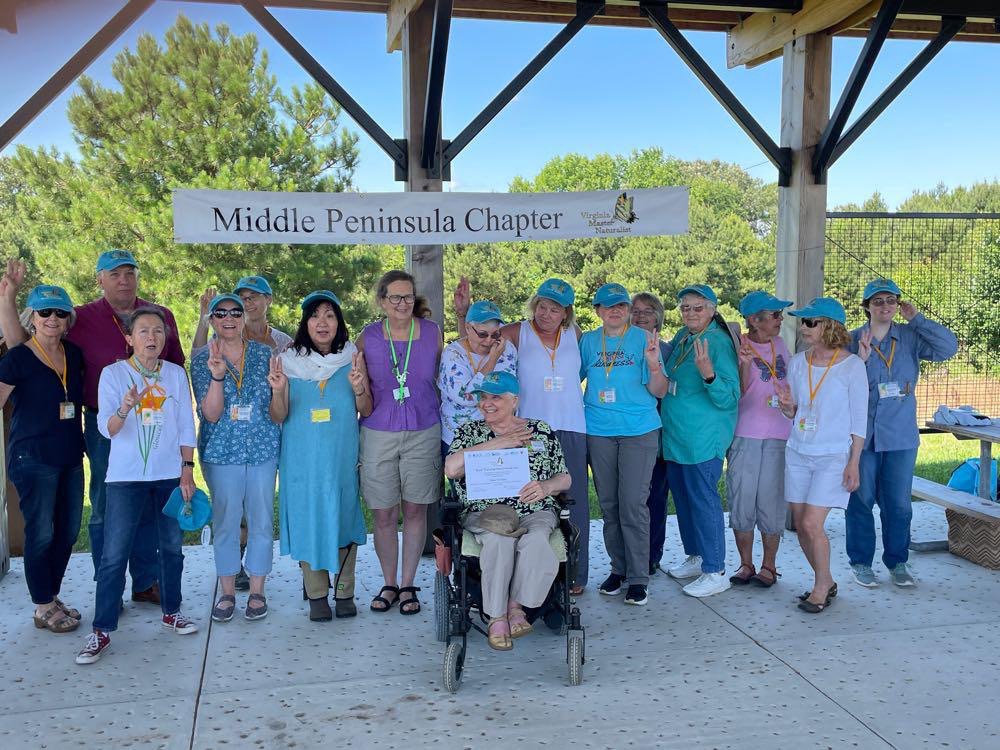 sixteen volunteers posed under a banner reading Middle Peninsula Chapter. The volunteers are each holding up three fingers.