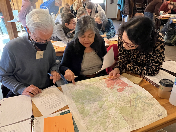 classroom of people working in groups, looking at topographical maps