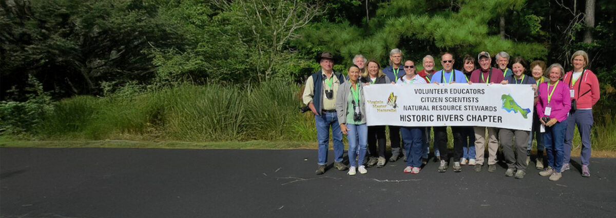 group of people posed holding a banner that reads Volunteer Educators, Citizen Scientists, Natural Resource Stewards, Historic Rivers Chapter
