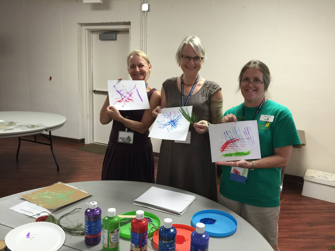 three people holding up artwork they have completed
