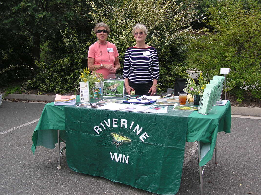 two volunteers at
a display table with Riverine VMN banner