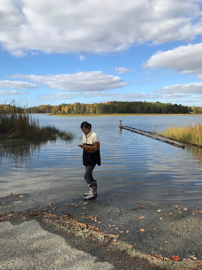 person at water's edge documenting with a cell phone