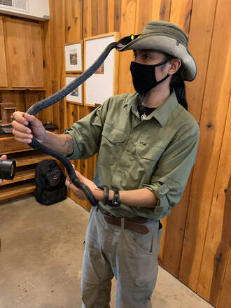 person wearing a hat and holding a snake that is climbing on him