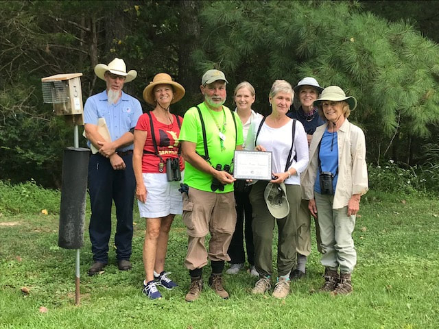 group of 7 people next to a bluebird box outdoors