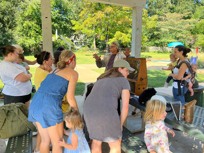 volunteer shows honeybees to young children and parents