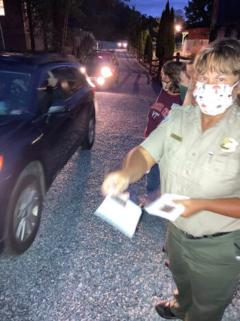 people handing flyers to drivers as they line up to enter a drive-in theater
