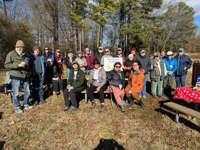 group of people outdoors by a Volunteers at Work sign