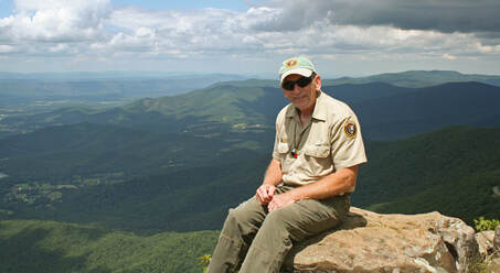 Jack Price sitting on a boulder with mountain views in the background