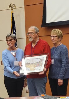 two volunteers receiving a framed picture at an awards ceremony