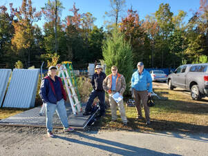 four volunteers posed next to a partially built shed