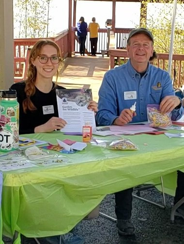 two people at a table outdoors with educational materials