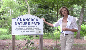 Woman stands outdoors next to a sign reading 