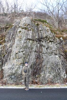 Photo of man on road in front of rock formation