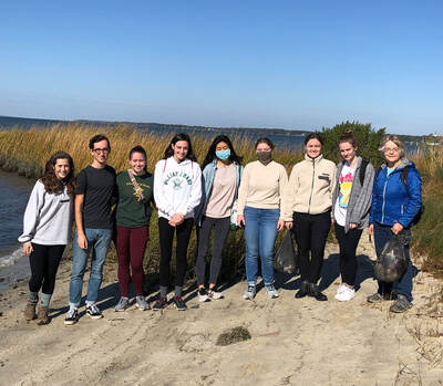 group of 8 college students posed on a beach with instructor Karen Duhring