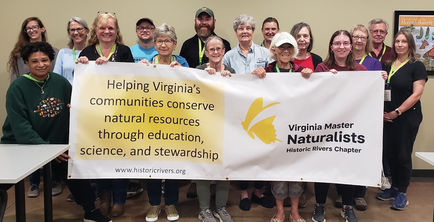 group of 16 people holding a banner that reads 'Virginia Master Naturalists, Historic Rivers Chapter, helping Virginia's communities conserve natural resources through education, science, and stewardship.'
