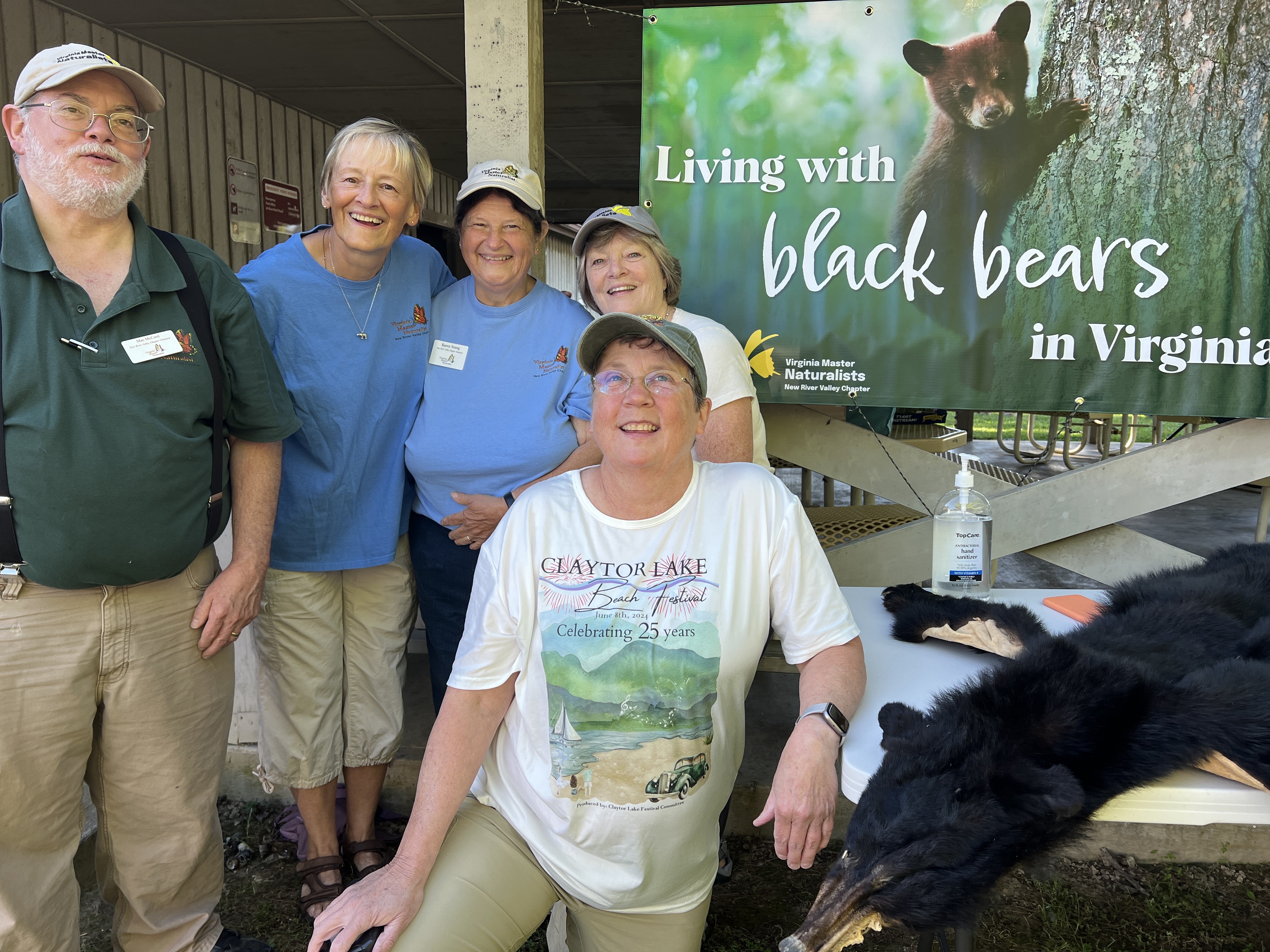 five volunteers posed next to a black bear pelt and a banner reading 'Living with Black Bears in Virginia'